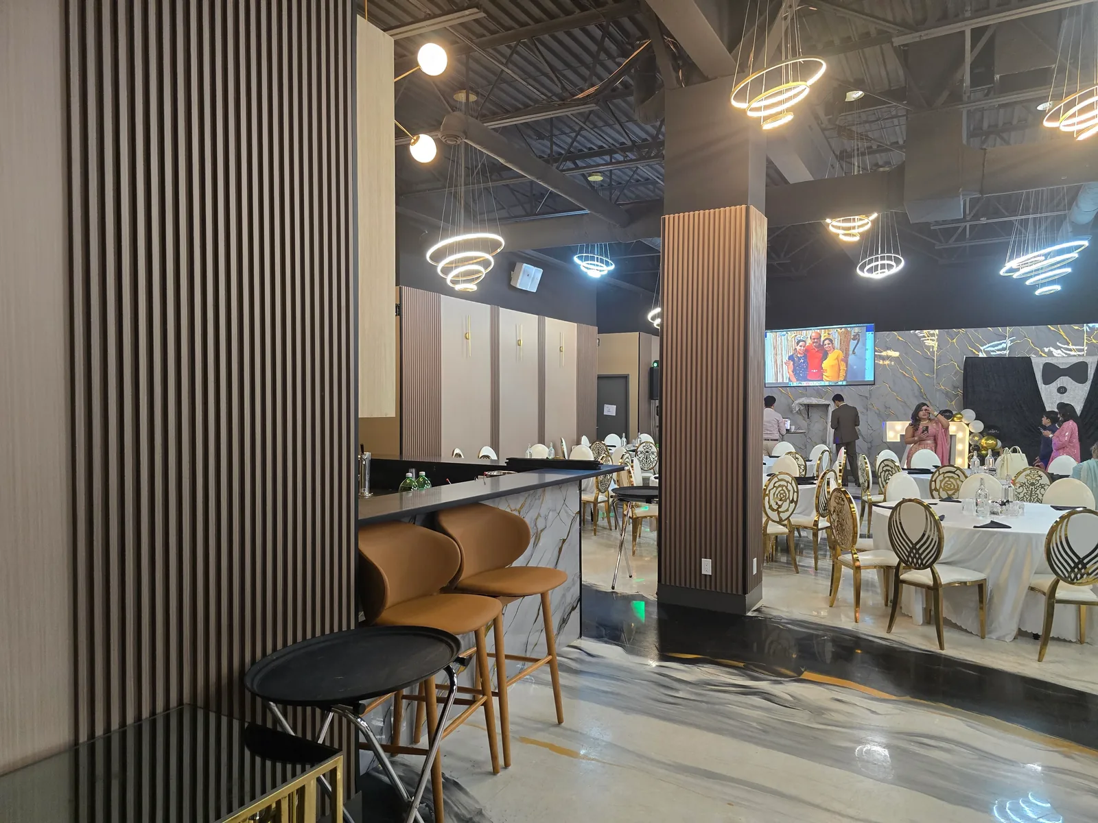 Bar counter and high-top seating at the Rawaayt banquet hall in Ellerslie, Edmonton, with the main event floor and guest tables beyond
